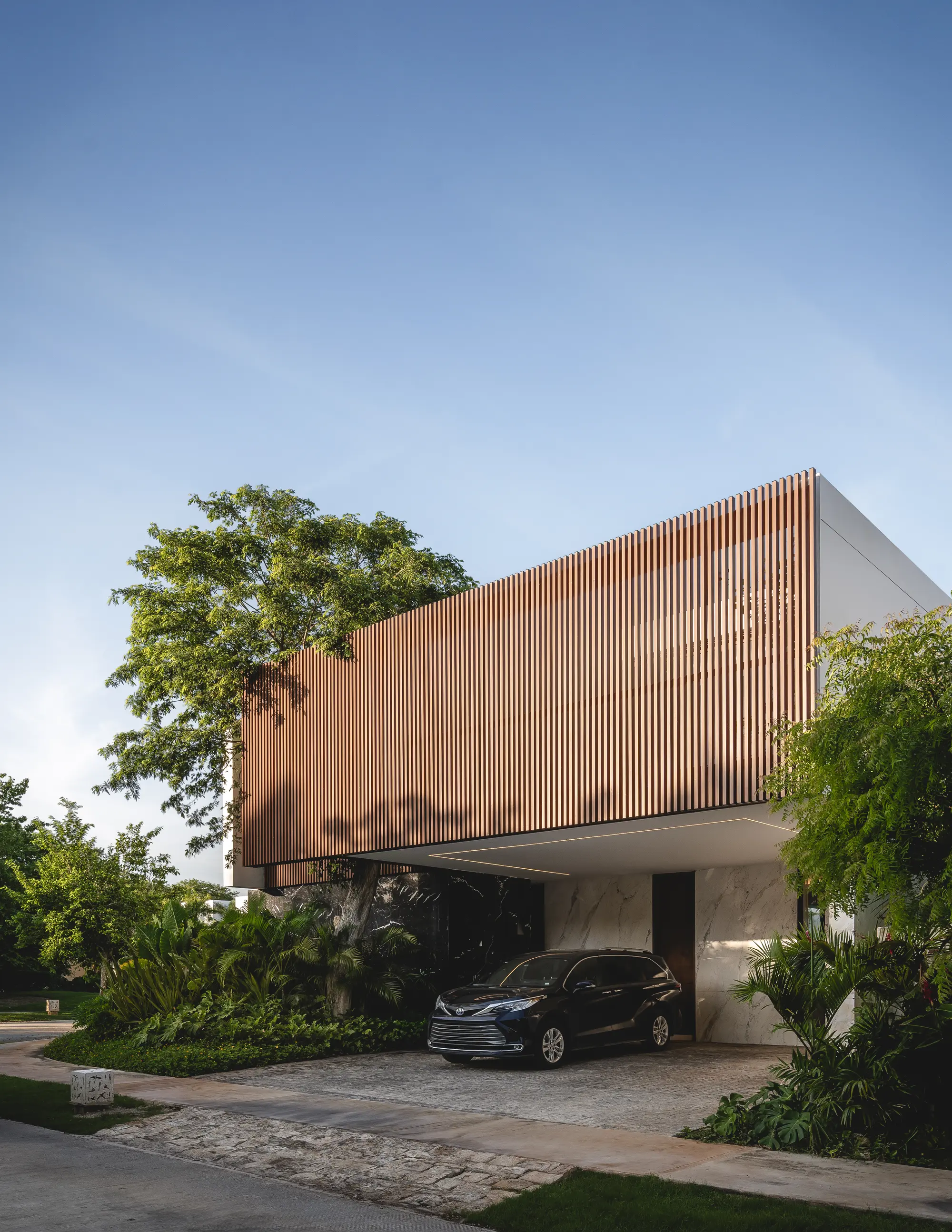 Fachada de Casa RO con celosía de madera sobre el jardín.