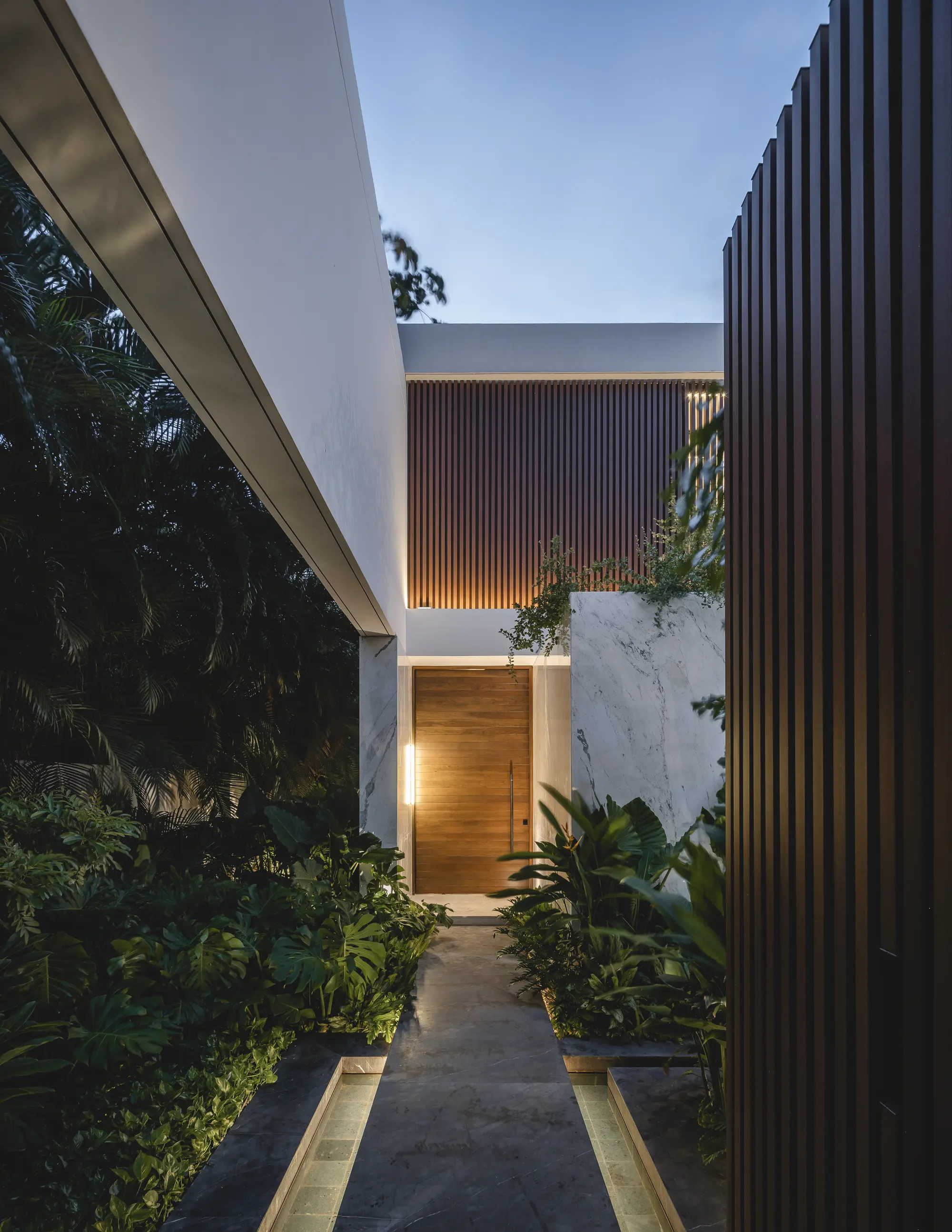 Acceso de Casa RO entre la celosía y la vegetación.